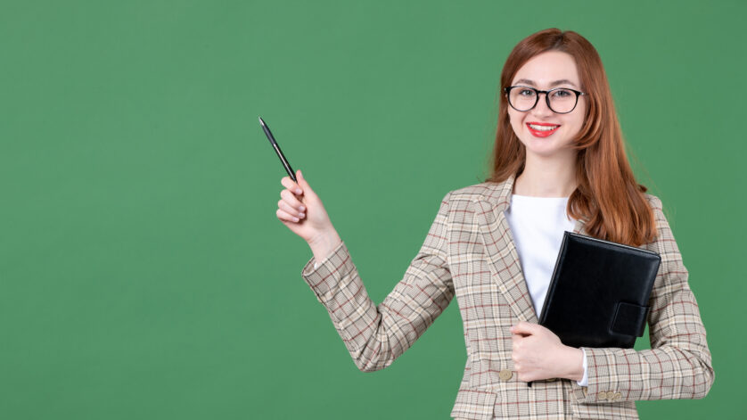 female-teacher-holding-notepad-green